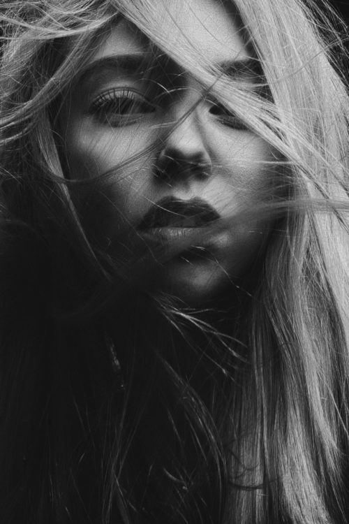 A black and white photo of a girl with her hair blowing.