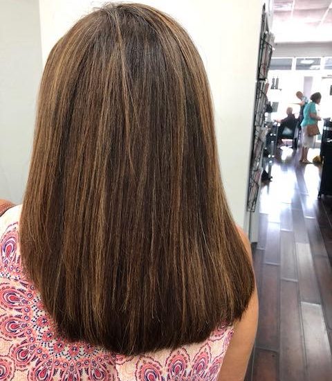 A woman with medium length, brown, silky hair after undergoing a keratin treatment.
